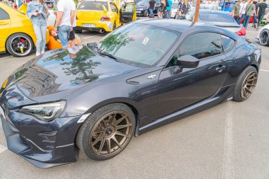 Koyu renkli bir spor araba, görünür aerodinamik elementler ve sonraki pazar whe Kyiv, Ukrayna 06-06-2024 ile birlikte, bir açık hava etkinliği gibi görünen bir yerde asfalt bir zeminde duruyor.