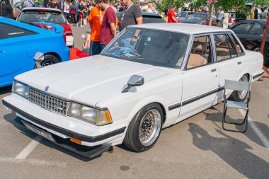 Çarşı sonrası tekerlekleri olan beyaz bir hatchback araba, düşük süspansiyonlu, ve büyük bir ön tamponunda belirgin delikler bulunan bir asfalt yüzey üzerine park edilmiş Kyiv, Ukrayna 06-06-2024