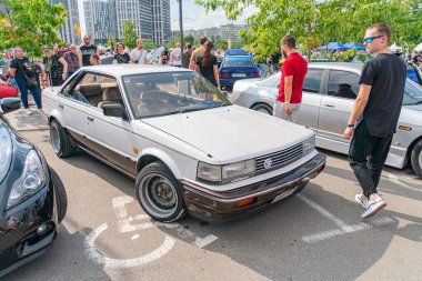 A vertical panorama shows an outdoor scene at what appears to be a car show, possibly a drift car exhibition A vintage car with flared wheel arches a Kyiv, Ukraine 06-06-2024 clipart