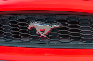 Kırmızı bir Ford Mustang arabasının ön ızgara bölgesinin yakın çekim görüntüsünde siyah arkaplan, su Kyiv, Ukrayna 06-06-2024 'e karşı ikonik gümüş dörtnala giden at amblemi yer alıyor.