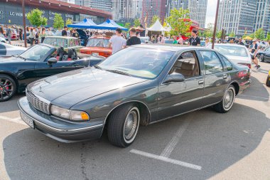 A black, four-door sedan from an earlier era is parked on a modern street with glass facade buildings in the background The vehicle has a sunroof and Kyiv, Ukraine 06-06-2024 clipart