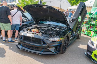 Kaputu açık siyah bir Ford Mustang motor bölmesini desteklerken, farlar ve ızgara modern ve agresif hatlar sağlıyor. Kyiv, Ukrayna 06-06-2024