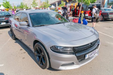 Gümüş renkli bir spor araba, yan aynaları ve kaportasında siyah aksanları olan asfalt bir yüzey önünde sola dönük duruyor. Araç özellikleri Kyiv, Ukrayna 06-06-2024