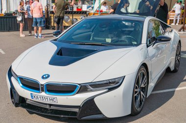Siyah aksanlı beyaz bir BMW i8 spor arabası, aerodinamik kaportasını ve LED farlarını sergileyen bir caddede park halinde duruyor. Araç ha Kyiv, Ukrayna 06-06-2024