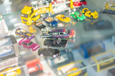 A colorful array of toy cars, ranging in size and hue, are meticulously arranged on a white shelf with a glass front, creating a visually engaging dis Kyiv, Ukraine 06-06-2024 clipart