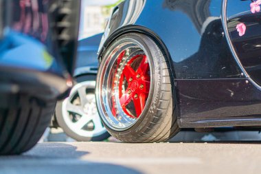 Bir arabanın arka tekerleğinin kırmızı jantları ve siyah bir merkezi vardır, muhtemelen jant kapağı ya da diski jantlarda görünür bir metin, açı ve kararlılık nedeniyle kısmen okunabilir durumdadır, Kyiv, Ukrayna 06-06-2024