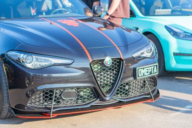 A black sports car with distinctive design elements is showcased in a close-up view, featuring a prominent grille and headlight assembly, red accents, Kyiv, Ukraine 06-06-2024 clipart