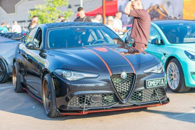 A black Alfa Romeo sports car is the main focus of a high-quality photograph taken in a public setting, likely at an auto show or similar event The v Kyiv, Ukraine 06-06-2024 clipart