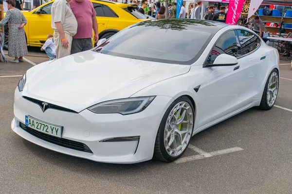 Caddenin sağ tarafına bakan beyaz bir Tesla Model S elektrikli arabası, d Kyiv, Ukrayna 06-06-2024 gibi parlak tasarım unsurlarını sergiliyor.