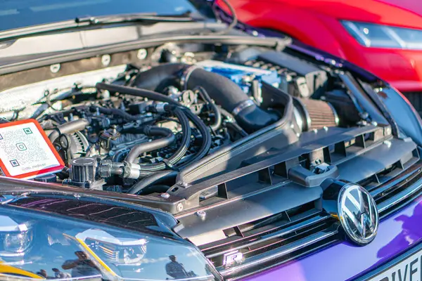 Bir Volkswagen otomobilinin motor bölmesi kaput açık, hava filtresi yuvası, pil, sıvı rezervuarları ve Ukrayna, Kyiv, Ukrayna 06-2024 de dahil olmak üzere uyarı etiketleri gösterilir.