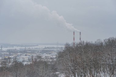 Görüntü kar, çıplak ağaçlar, sanayi veya elektrik santrali, uzun bacalar, beyaz duman, bulutlu gökyüzü, ikamet veya eğitim binası Kyiv, Ukrayna 01-14-2024