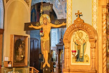 Image depicts a Byzantine church interior, featuring a large crucifix with Jesus Christ, liturgical iconostasis, saints or apostles icons, mosaics, warm lighting, and sol Kyiv, Ukraine 01-14-2024 clipart