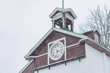 Saat kulesi olan karla kaplı bir okul binası, çan kulesinde Amerikan bayrağı, çok katlı pencereler, bulutlu Kyiv, Ukrayna 01-14-2024