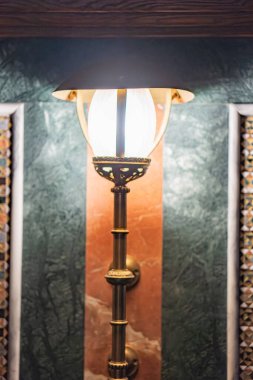 Döşeme kaplamalı duvarın yakın görüntüsü eski moda bir lamba direği ile lamba pirinç ya da bronzdur, filigran detaylarıyla süslenmiştir ve çift aydınlatma için tasarlanmıştır görüntü Art Nouveau ya da