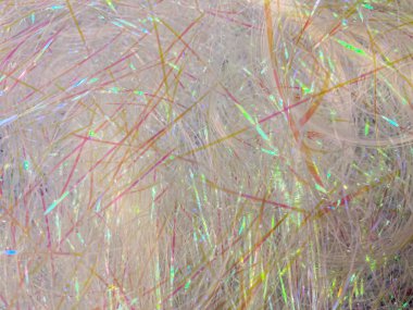 Yakın planda, bulanık bir arkaplan üzerine kurulmuş beyaz, gri, pembe ve turuncu renk karışımlı saç telleri görülür.