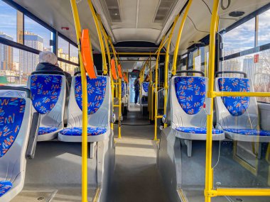 Gün ışığında mavi desenli koltuklara ve sarı metal direklere odaklanan bir otobüs görüntüsü. Şehir manzarası pencerelerden görülebiliyor. Kyiv, Ukrayna, 03-15-2024