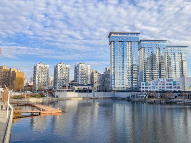 Rıhtım binaları, yansıtıcı su, rıhtım, parçalı bulutlu gökyüzü Kyiv, Ukrayna, 03-15-2024