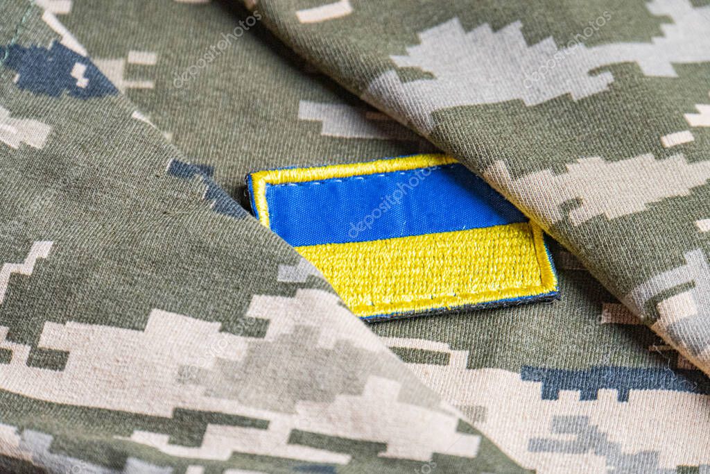 Ukrainian flag on the military uniform of the Ukrainian army. The concept of war and arms supplies. Pixel army pettern militaria khaki. Ukrainian national symbol and defense symbol. Yellow-blue