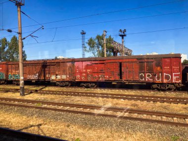 Grafiti yapan eski, paslı, kırmızı bir tren vagonu endüstriyel bir zemine çarpıyor. Gündüz saatlerinde hiç kimse Kyiv, Ukrayna 06-02-2024 'ü göremez.