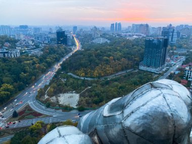 Panoramic view of an urban landscape at duskdawn, overcast sky, large metallic spheresdomes, high-rise buildings, traffic, waterfront areariver, wide-angle photograph Kyiv, Ukraine 06-02-2024 clipart