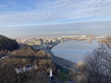 Panoramic cityscape with tranquil waterway, bustling traffic, tall buildings, patches of vegetation, vibrant colors, and harmonious coexistence of man-made structures and Kyiv, Ukraine 11-02-2024 clipart