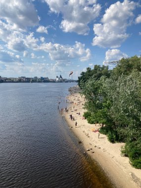 Sakin bir sahil manzarasının panoramik görüntüsü, birkaç küçük ada, yeşilimsi rengi yansıtan bir su, ağaçlar ve yapraklar, günlük kıyafetleri, dağınık gökyüzü