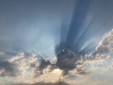 Image showcases a sunbeam phenomenon crepuscular rays during sunrise or sunset, with fluffy white clouds and soft pastel blue tones The photograph captures the interplay of light and clouds clipart