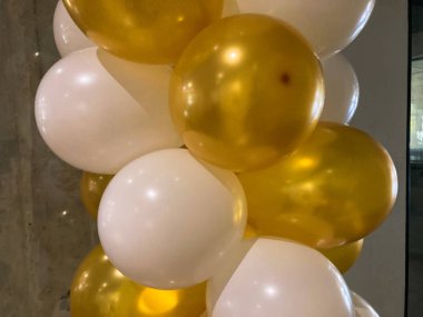 A cluster of shiny gold and white balloons, possibly at a celebration or party. a clipart