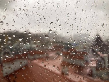 Penceresinde düzensiz damlalar olan yağmurlu bir şehir manzarası. a