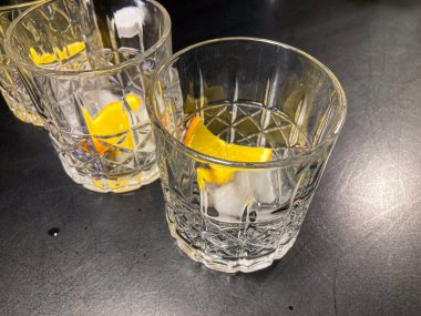 İki bardak muhtemelen votka, buz küpleri ve limon dilimleriyle süslenmiş, ahşap bir yüzeyde. a