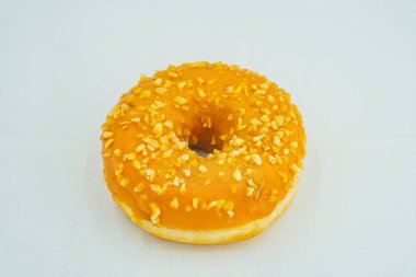 Açık gri bir yüzey üzerinde turuncu tohum ya da fındıklı tek bir canlı sarı donut sadece donut görünümüne ve dokusuna odaklanır.