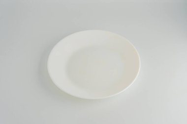 Kullanılmış beyaz bir tabağın yakın çekim görüntüsü, yemek kalıntıları, kapalı bir ortamda çekilmiş, muhtemelen bir mutfak veya yemek alanı. Fotoğraf basit ve belgesel.