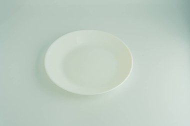 Açık gri ya da açık gri bir yüzeye yerleştirilmiş besin kalıntıları olan temiz, beyaz bir tabağın görüntüsü.