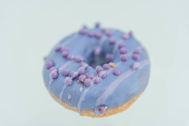 Mor benekli tek bir mavi donutun görüntüsü, nötr bir arkaplana yerleştirilmiş.