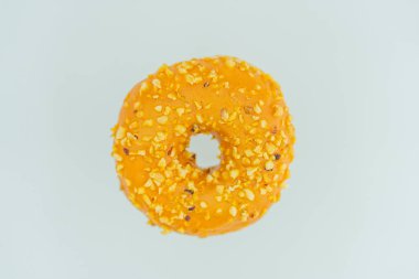 A single, orange glazed doughnut with a golden brown base and small yellow specks on top is the central focus of this image, set against a plain background clipart