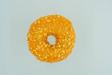 Görüntü canlı, turuncu jöleli, gri arka planda sarı benekli bir donut gösterir. Çöreğin ortasında bir delik vardır ve çerçevenin tek konusudur.