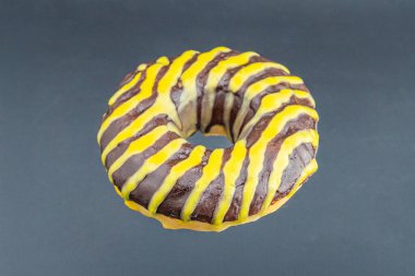 Tek bir donutun yakın plan fotoğrafı, kremalı, birbiriyle zıt renkte sarı ve çikolata karışımlı bir girdap tasarımı.