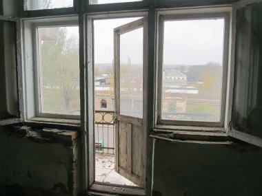 İhmal edilmiş eski bir binanın iki açık penceresinden çekilen bir iç mekan fotoğrafı.