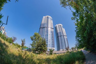 Aksilikler, şeffaflık ve sağlamlıkla çelişen iki modern yüksek binalar, Ukrayna, 06-17-2024 kentsel ortamında yemyeşil ile uyumlu bir şekilde yaşarlar.