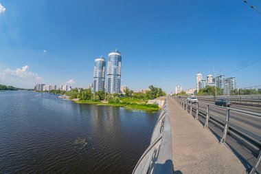 Modern bir şehir manzarası, solunda iki çarpıcı yüksek binası bulunan eski ve yeni mimarinin bir karışımını içeriyor. Birinin kendine özgü yuvarlak bir tacı ve diğerinin de bo Kyiv, Ukrayna 06-17-2024