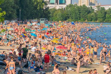Sakin, davetkar bir su kütlesi, ağaçlarla kaplı tepeler, renkli şemsiyeler, eğlence tesisleri ve dinlenme arayışında olan meşgul ziyaretçiler Kyiv, Ukrayna 06-17-2024