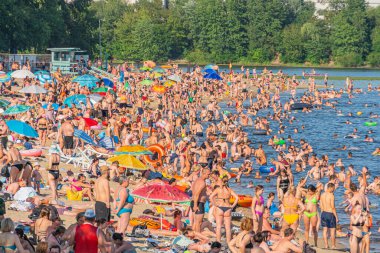 Organik mimarinin, renkli şemsiyelerin ve organize tasarım ekleyen şemsiyelerin yer aldığı canlı bir sahil sahnesi. İnsanlar bu elementlerle etkileşim halindeler: Kyiv, Ukrayna 06-17-2024