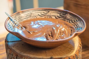 Parlak, yapışkan bir maddenin yakın plan görüntüsü. Büyük ihtimalle çikolata ya da benzeri bir kabın içinde, ahşap bir yüzey üzerinde.