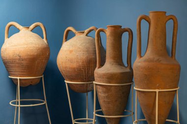 Metal bir arkaplanda duran dört eşsiz terracotta vazosu. Her vazonun farklı şekilleri, boyutları ve sapları var.