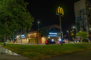 Görüntü, aydınlık kentsel bir gece sahnesini gösteriyor. Binalar ve McDonalds restoranı, aydınlık sokakların altında çatışma veya savaş izi yok Kyiv, Ukrayna 08-24-2024