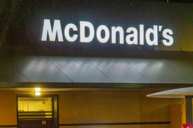 Karanlık gökyüzü altındaki McDonalds restoranının görüntüsü, altın kemerler aydınlatılmış. Olay yerinde askeri teçhizat veya personel yok. Sivil altyapıya odaklan ve muhtemelen Kyiv, Ukrayna 08-24-2024