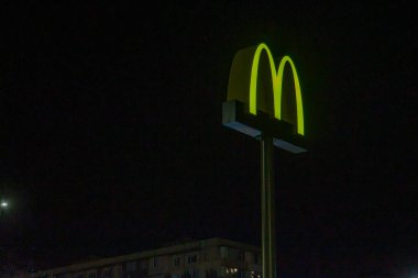 Görüntü, Ukrayna 'nın Ukrayna 08-24-2024 logosuna odaklanarak gece aydınlatılmış bir McDonalds restoranını gösteriyor.
