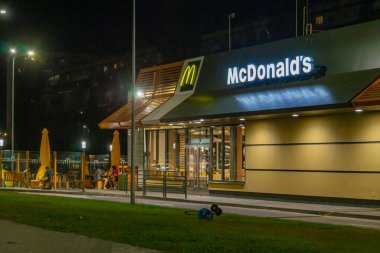 Görüntü, uluslararası ticari varlığı ve Kyiv, Ukrayna 08-24-2024 ekonomik bağlantılarını sembolize eden bir gece McDonalds restoranını gösteriyor.