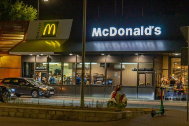 Park halindeki Kyiv, Ukrayna 08-24-2024 arabalı ışıklı bir McDonalds restoranında gece sahnesi.
