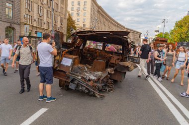 Görüntü, muhtemelen Rus-Ukrayna çatışması ile ilgili hasarlı bir askeri aracın şehir sahnesini gösteriyor. Çevre, tartışmalı bir bölge olduğunu gösteriyor. Siviller ise p Kyiv, Ukrayna 08-24-2024